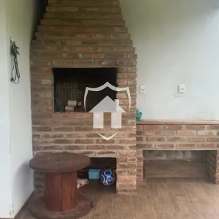 Parede de tijolos com lareira e mesa de madeira em um interior.