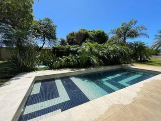 Foto externa mostrando uma piscina com revestimento azul e branco em um dia ensolarado.