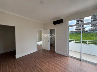 Ambiente interno com piso de madeira e porta de vidro abrindo para o exterior.