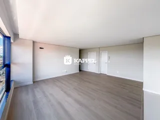 Sala de estar ampla com piso de madeira clara e paredes brancas.