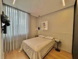 Quarto com cama e cortinas claras na sala.