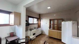 Interior da cozinha com armários de madeira e piso de cerâmica.