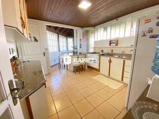 Cozinha com armários brancos e piso de cerâmica em uma residência.