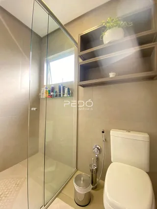 Foto de um banheiro com box de vidro e vaso sanitário branco.