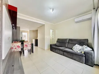 Sala de estar com sofá cinza e piso de cerâmica clara.