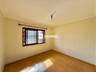 Vista interna de um cômodo com piso de madeira e janela.