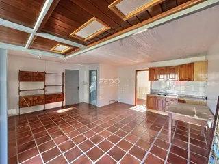 Sala de estar com piso de cerâmica avermelhada e forro de madeira.