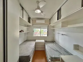 Quarto com duas camas e estantes em um imóvel no Brasil.