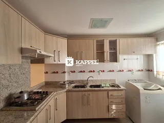 Cozinha moderna com armários de madeira clara e bancadas de granito.