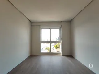 Ambiente interno de uma sala com piso de madeira e grande janela.