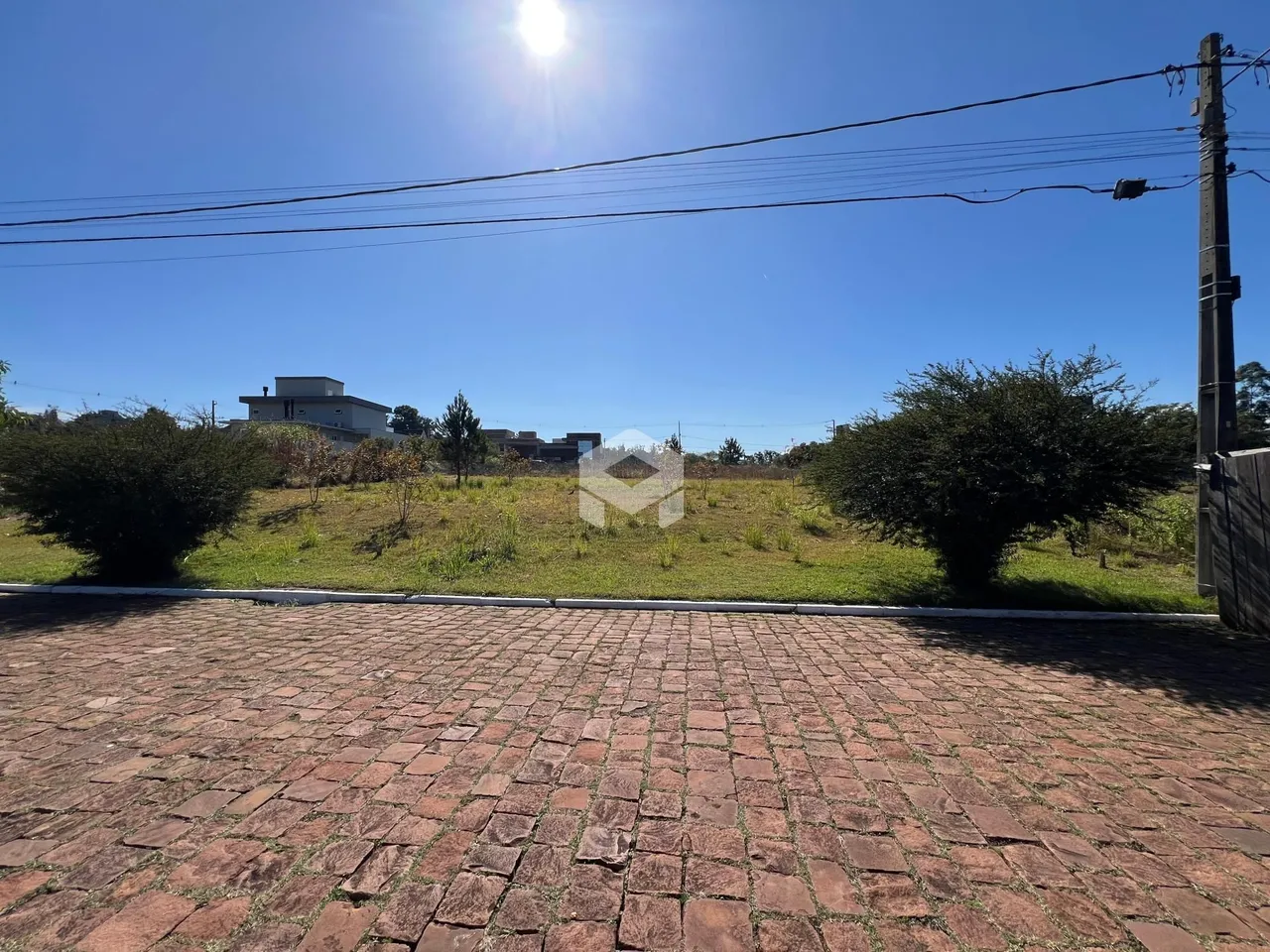 Vista externa de uma propriedade com gramado e calçamento de tijolos.