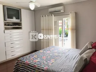 Quarto com cama e janela com cortinas brancas.