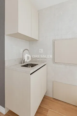 Vista da cozinha com armários brancos e bancada clara.