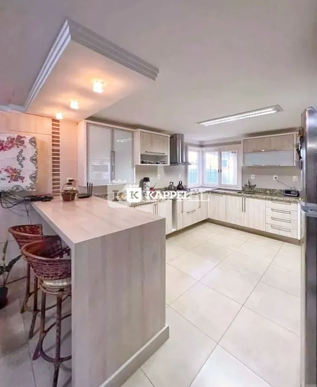 Cozinha moderna com ilha central e armários brancos em um imóvel.