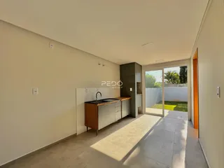 Vista da cozinha com armários brancos e bancada de madeira em um ambiente claro.