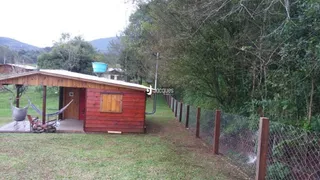 Vista externa de uma propriedade com cerca e vegetação.