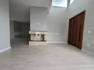 Ambiente interno de uma sala ampla com lareira e piso de madeira clara.