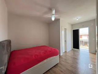 Quarto com cama e piso de madeira clara em um imóvel no Brasil.