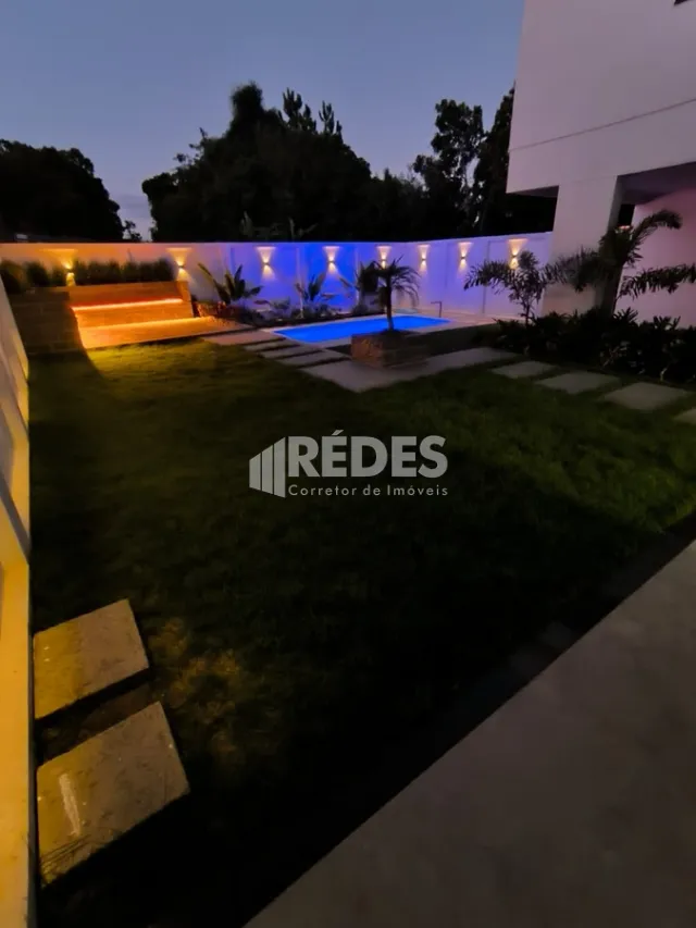 Vista noturna de uma piscina e jardim de uma propriedade em Lajeado.