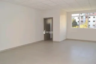 Uma sala vazia com paredes brancas e piso claro.