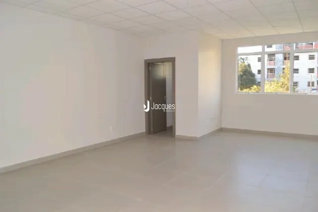 Uma sala vazia com paredes brancas e piso claro.