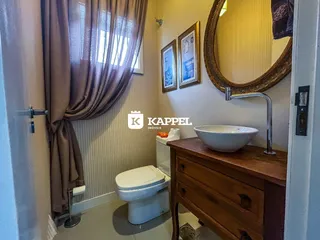 Banheiro com pias, vaso sanitário e armário de madeira.