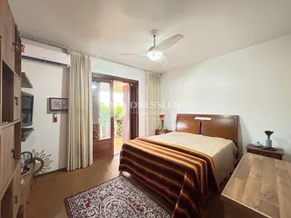 Quarto com cama de madeira e cortinas claras.