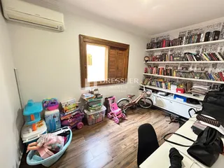 Sala de estar com piso de madeira e estante de livros na parede.