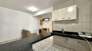 Vista interna de uma cozinha com armários brancos e piso de cerâmica.