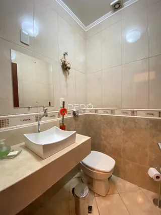 Banheiro com azulejos claros e pia branca.