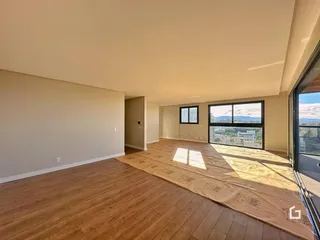Sala de estar ampla com piso de madeira e vista para a paisagem.