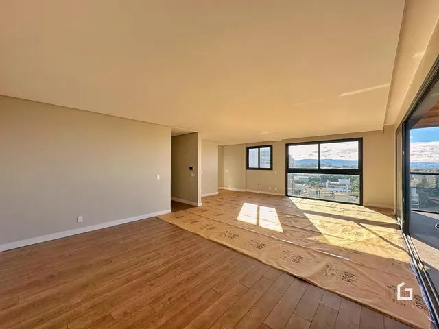 Sala de estar ampla com piso de madeira e vista para a paisagem.