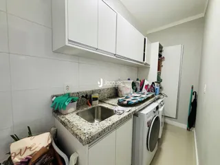 Vista da cozinha com armários brancos e bancada de granito.