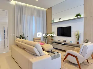 Sala de estar moderna com sofá grande e televisão na parede, decorada com plantas.