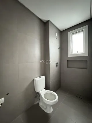 Foto interna de um banheiro com piso e paredes em tom de cinza.