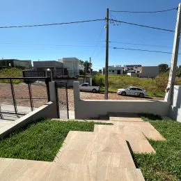 Vista externa de um pátio com degraus de concreto e vegetação.
