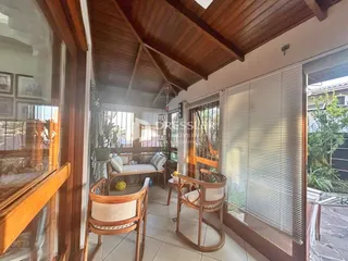 Vista interna de uma sala com teto de madeira e portas de vidro.