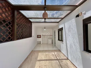 Corredor interno com teto de vidro e paredes brancas em uma residência.