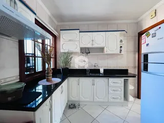 Vista da cozinha com armários brancos e bancadas escuras.