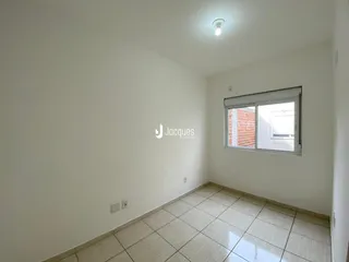 Sala de estar com piso de cerâmica clara e parede branca.