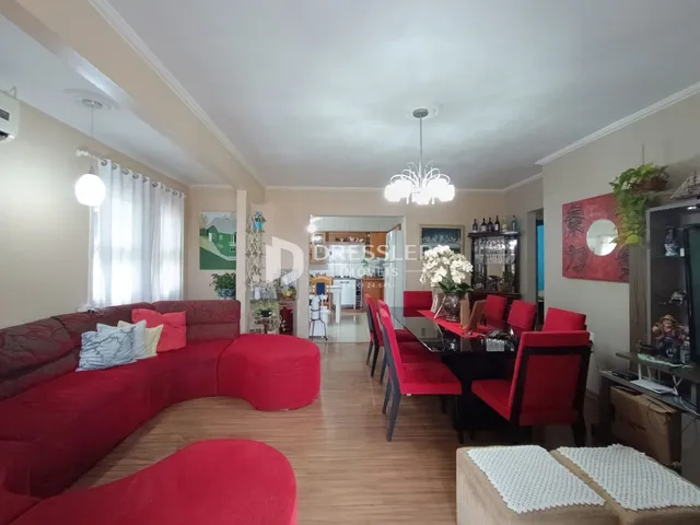 Sala de estar com sofá vermelho e mesa de jantar em um imóvel no Brasil.