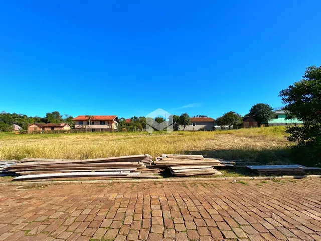 Vista de uma paisagem rural com casas ao fundo e um campo de grama seca.