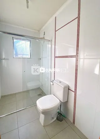 Foto interna de um banheiro com piso de cerâmica e box de vidro.