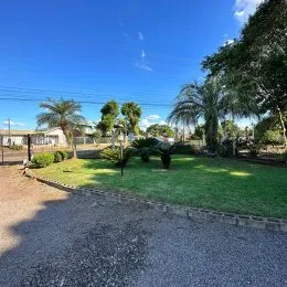 Vista externa de um jardim com grama e árvores em uma propriedade.