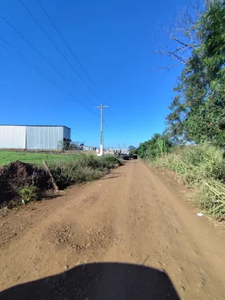 Vista de uma estrada de terra em uma área rural sob um céu azul.