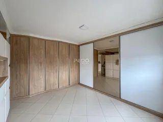 Interior de uma sala com armários de madeira e piso claro.