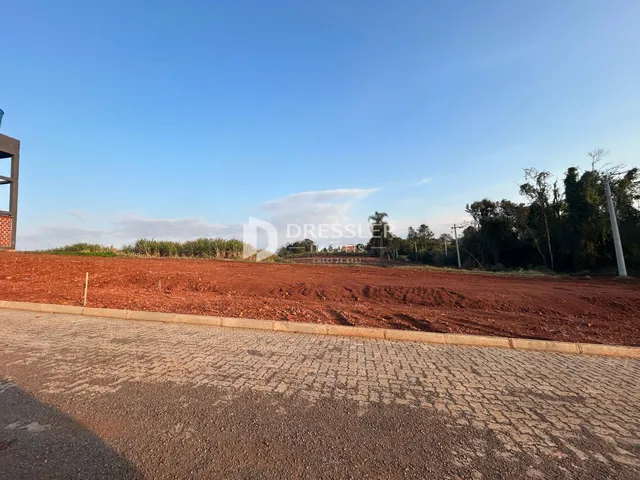 Vista da propriedade com terra exposta e vegetação ao fundo.