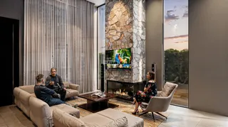 Uma sala de estar moderna com sofá e lareira em um ambiente com grandes janelas.