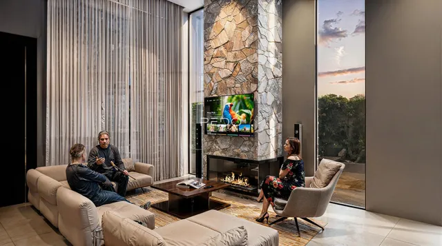 Uma sala de estar moderna com sofá e lareira em um ambiente com grandes janelas.