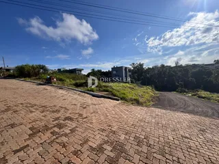 Vista da propriedade com pavimento de tijolos e vegetação ao fundo.